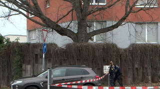 Polizeibeamte nehme mit Flatterband eine Absperrung vor, nachdem ein 42-Jähriger am Vortag in eine Wohnung eingedrungen ist und mit einem Messer auf ein Ehepaar eingestochen hat. Polizisten nahmen den Verdächtigen nach der Tat noch in der Wohnung des Paares fest. Darüber hinaus wurde in dem Gebäude eine tote 73-Jährige gefunden. Sie sei im Zuge der Ermittlungen zu dem Messerangriff als vermisst gemeldet worden.