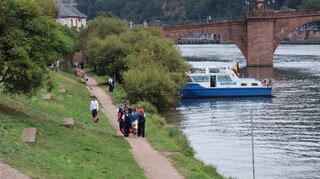 Polizisten führen den Mann ab, der in den Neckar gesprungen ist.
