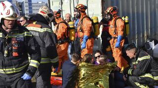 Im Vordergrund versorgt die Feuerwehr Wien die in Goldfolie eingehüllten Verletzten, im Hintergrund laufen Mannheimer ATF-Spezialkäfte mit Schutzanzügen.