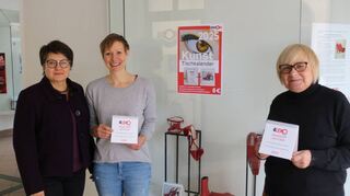 Larysa Kay-Kulakowski (v.l.), Janina Otte und Brigitta Eckert präsentieren den Kunstkalender des Lernmobils.