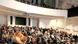 Blick in das Auditorium im Technoseum, wo die Kinder gespannt dem Vortrag von Philipp Schmid über den Welterfolg der Firma Lego lauschen. „MM“-Maskottchen Fred Fuchs sitzt in der ersten Reihe.