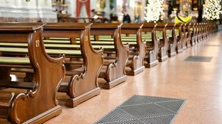 Zwischen 15 und 19 Grad: die Gitter der Heizungsschächte in der Jesuitenkirche vor Kirchenbänken.