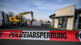 Der Bagger steht neben einem Autohaus in Tauberbischofsheim hinter einer Polizeiabsperrung. Nach der zerstörerischen Baggerfahrt und tödlichen Polizeischüssen auf den Fahrer in Tauberbischofsheim laufen die Ermittlungen zu dem Geschehen.