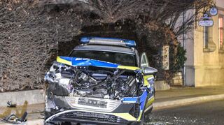 Ein demoliertes Polizeiauto steht auf einer Straße. Ein Mann hat in Grünsfeld einen Bagger gestohlen, damit eine Baufirma und Streifenwagen beschädigt und drei Polizisten verletzt.