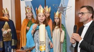 Sternsingerin Emily Broszies (8) zündet mit Karl Jung eine Kerze für die Stadt an.