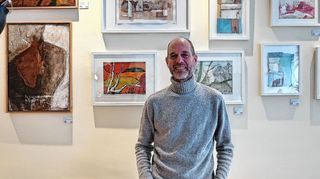 Künstler Frank Schulze vor einigen seiner insgesamt 60 Bilder, die im Café Susa in Wallstadt hängen.