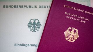 Eine Einbürgerungsurkunde der Bundesrepublik Deutschland (l) und ein deutscher Reisepass liegen auf einem Tisch. Geht es nach Friedrich Merz soll es leichter werden, den deutschen Pass zu entziehen.