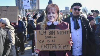Eine Demonstrantin war bei der Kundgebung "Wir sind die Brandmauer!" auf dem Alten Meßplatz in Mannheim als Angela Merkel verkleidet.