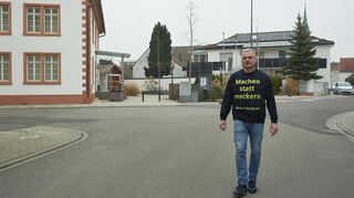 Macht sich auf den Weg in Richtung Verwaltung: FDP-Bürgermeisterkandidat Werner Kruck zwischen dem Bobstädter Rathaus (links) und seinem energetisch saniertem Zuhause rechts in Hintergrund.