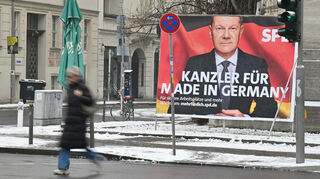 13.02.2025, Berlin: Eine Fußgängerin geht an einem großflächigen Wahlplakat mit Bundeskanzler Olaf Scholz (SPD) vorbei.