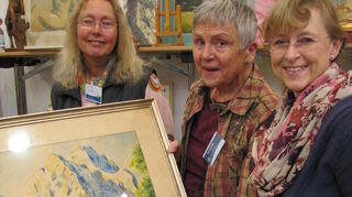 Eine Alpenlandschaft wartet auf neue Besitzer. Das kundige Kunst-Trio Gabriele Vahldieck, Karla Schlichtmann und Britta Bock (von links) berät am Stand.