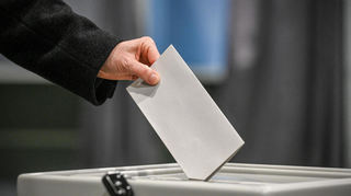 Eine Person wirft einen Stimmzettel in eine Wahlurne am 6. Februar 2025 in einem Wahllokal in Bonn.