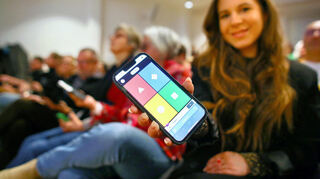 Eine Frau im Publikum zeigt, wie das Quiz per App "Kahoot!" funktioniert.