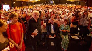 Intendant Michael Kötz (Mitte, stehend) betritt 2022 vor gefüllten Rängen die Bühne des Festivals des Deutschen Films in Ludwigshafen.