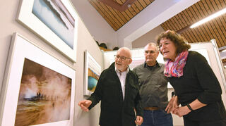 Fotokunst im Schriesheimer Feuerwehrgerätehaus: Hans Assmus (l.), Michael Kunze und Gabriele Mohr-Nassauer betrachten die ausgestellten Werke.