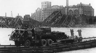 Die amerikanische Pontonbrücke zwischen Mannheim und Ludwigshafen. Im Hintergrund sind die zerstörte Rheinbrücke und die Trümmer der Walzmühle zu sehen.