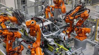 Industrieroboter arbeiten an der Karosserie für einen vollelektrischen Porsche Macan im Werk Leipzig.