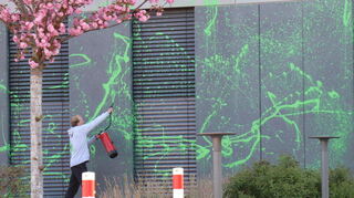Ein Mann beschmiert ein Gebäude in Leimen mit grüner Farbe