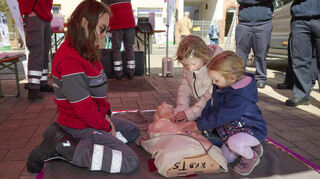Am Stand des Roten Kreuzes übt Anna Kreider mit zwei Kindern die Reanimation.