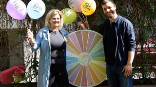 Mit Glücksrad und Luftballons: Pfarrerin Nina Roller und Dekanatsreferent Matthias Leis vom Team des ökumenischen Kirchenstands, den es erstmals auf dem Maimarkt gibt.
