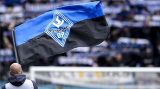 Ein Fan des SV Waldhof Mannheim schwingt eine Fahne mit dem Logo des Vereins.