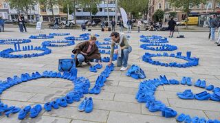 Künstler Frank Schlottmann und eine Teilnehmerin platzieren die letzten Schuhe für die Kunstinstallation.