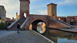 Abendstimmung in Comacchio. Der Hauptort liegt nicht direkt an der Adria, trotzdem ist das Wasser aufgrund zahlreicher Kanäle allgegenwärtig. Unterhalb der Trepponti-Brücken münden mehrere Kanäle in einen.