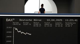 Eine Frau geht auf der Besucherempore der Frankfurter Wertpapierbörse oberhalb der Anzeigetafel mit der Dax-Kurve vorbei.