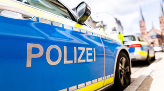 Zwei Einsatzfahrzeuge der Polizei stehen in Freiburg am Straßenrand.