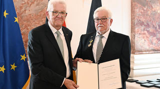 Ministerpräsident Winfried Kretschmann (l.) überreicht den Landesverdienstorden an den Mannheimer Klaus Schirdewahn.