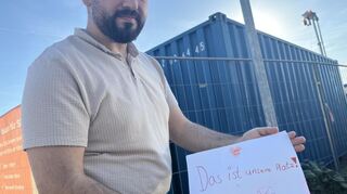 Samed Akyüz zeigt ein Kinderbild mit der Aufschrift "Das ist unser Platz!". Anwohner im Stadtteil Hochstädt protestieren gegen den Wegfall einer Grünfläche, auf der ein 24/7-Self-Storage gebaut wird.