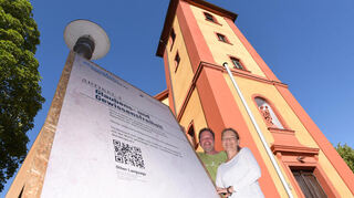 An der katholischen Kirche ist Artikel 4 ausgestellt, daneben stehen die Initiatorin Birgitta Schmücker (r.) und Franky Kaiser (l.), der sie bei der technischen Umsetzung unterstützte.