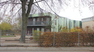 Auf der Rückseite des grünen Gebäudes entsteht das Außengelände der Kinderkrippe. Rechts ist ein Ansatz der Mehrzweckhalle zu sehen. Das Bild stammt aus dem Jahr 2020.