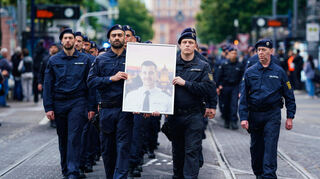 Polizisten tragen bei einem Trauermarsch für den bei einer Messerattacke in Mannheim tödlich verletzten Polizisten Rouven Laur dessen Bild. Er starb nach der Attacke am 31. Mai 2024.