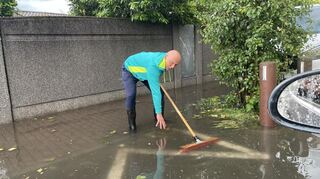 Anwohner Frank Amato befreit einen Gully-Deckel von Laub. Sofort saugt der Kanal das Wasser ab.