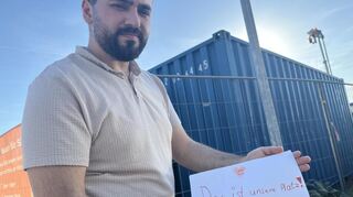 Hochstätt-Anwohner Samed Akyüz zeigt ein Kinderbild mit der Aufschrift "Das ist unser Platz!".