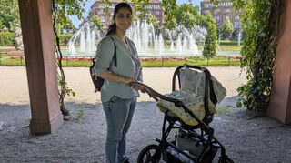 Eren zeigt, wie sie ihr Neugeborenes vor Hitze schützt: Im Schatten bleiben und mit hellen Mulltüchern als zusätzlichem Sonnenschutz.