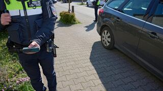 Mit einem Messgerät überprüft ein Bediensteter der Stadtpolizei, ob der Autofahrer genug Platz auf dem Gehweg freigelassen hat.