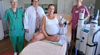 Die beiden Ärztinnen Stephanie Snyder-Ramos und Petra Beuter-Winkler, im Kreißsaal mit einer schwangeren Patientin und Hebamme Sarah Kuhn (v.l.). Am rechten Bildrand die Lachgas-Anlage mit der Cracking-Unit in der Mitte.