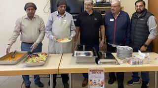 Männer der Lampertheimer Ahmadiyya Muslim Gemeinde geben selbst gekochtes Essen aus.