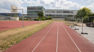 Auf diesem Sportfeld wird das neue Lessing-Gymnasium gebaut werden. Im Hintergrund ist das jetzige LGL zu sehen. Während der Altrheinhallensanierung wird hier im Herbst eine Traglufthalle für Schul- und Vereinssport aufgebaut.