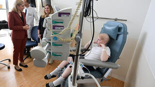 Bundesgesundheitsministerin Nina Warken (links) spricht bei ihrem Besuch im Zentrum für Kinder und Jugendmedizin im Universitätsklinikum Heidelberg mit einem krebskranken Jungen und dessen Mutter.