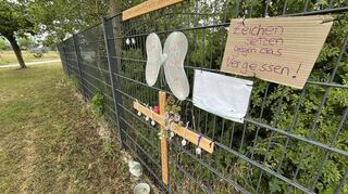 Manche Bürger haben Kreuze und Pappschilder am Zaun angebracht.