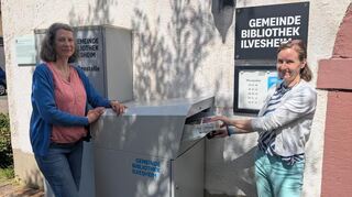 Caroline Rödel-Braune (r.) und Christina Schobert am neuen Schrank, in dem Bücher außerhalb der Öffnungszeit zurückgegeben werden können.