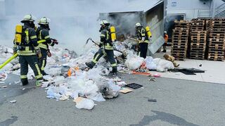 Aufwendige Löscharbeiten: Die Feuerwehr verhindert, dass der Brand auf die Holzpaletten überspringt.