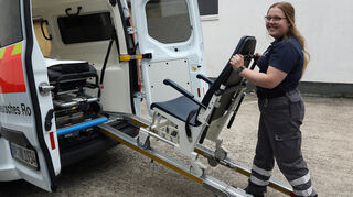 Bereitschaftsleiterin Jessica Wetzel schiebt den alten Transportstuhl in den Krankenwagen. Der neue passt von den Ausmaßen genau auf die Führungsschienen, davon haben sie sich bei der Messe überzeugt.