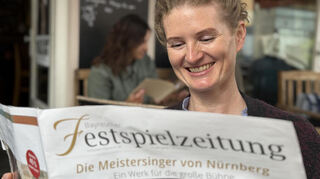 Eva Röthke, die 1. der beiden Soloharfenistinnen des Mannheimer Nationaltheaterorchesters, beim Lesen der Bayreuther Festspielzeitung. Röthke wirkt im Festspielorchester mit und sitzt hier in einem Café in der Bayreuther Innenstadt.