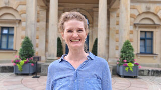 Eva Röthke, die 1. der beiden Soloharfenistinnen des Mannheimer Nationaltheaterorchesters, vor dem Königsportal des Bayreuther Festspielhauses. Auch 2025 ist Röthke wieder Teil des Festspielorchesters, mit dem sie den „Ring“, „Tristan“ und „Parsifal“ spielt.