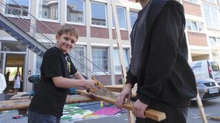 Gabriel (11) sägt mit Betreuer Lukas Noffz eine Holzlatte für das Bühnenbild durch.