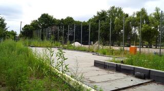 Seit Februar 2025 herrscht Stillstand auf dem Baugelände am Lochgärtenweg 10. Das Kellergeschoss des Jugendhauses ist fertig. Auf dem Grundstück wächst mittlerweile das Unkraut. Auf dem seit September 2024 gesperrten Bolzplatz daneben (siehe hinter dem Zaun) werden Baumaterialien gelagert.